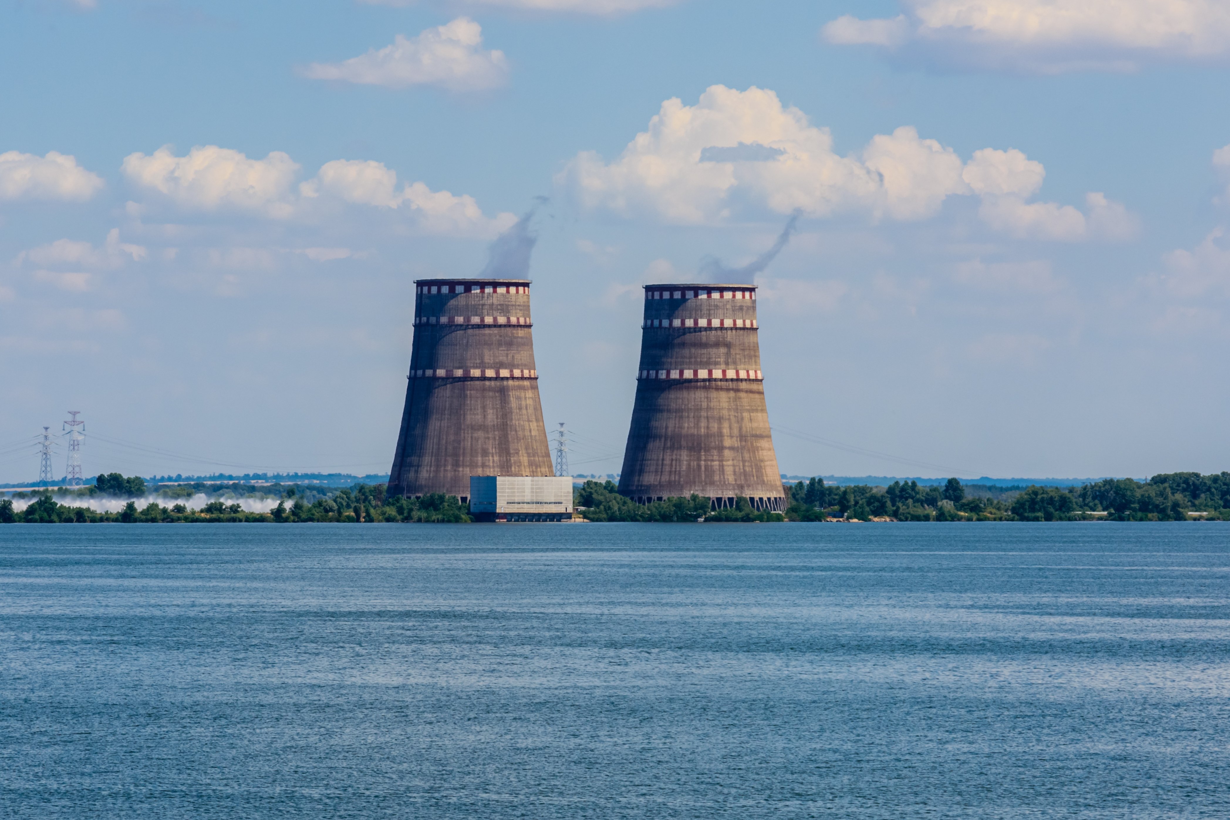 Kjernekraftverk med to kjøletårn, og vann i forgrunnen.