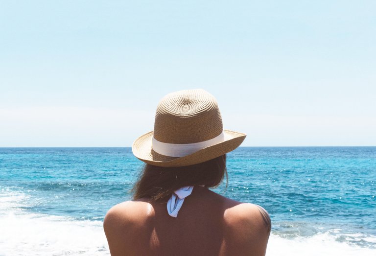 dame med hatt som titter ut over havet